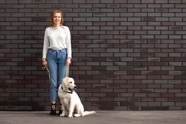 Jeune belle fille urbaine se tient avec un chien dans la rue une femme avec un golden retriever