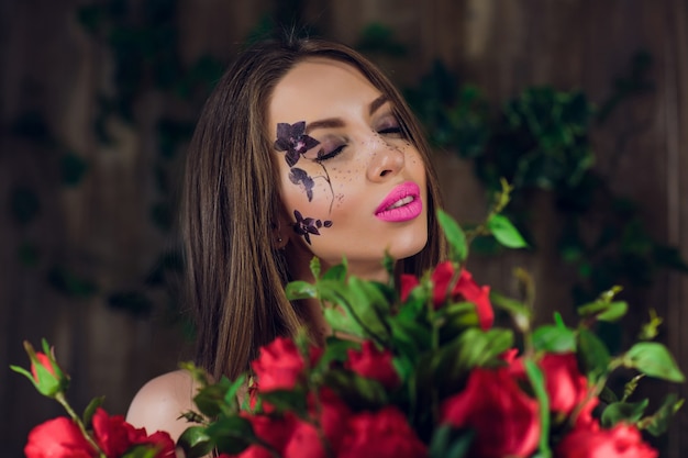 Jeune belle jolie fille debout et tenant la boîte avec des roses rouges. Vogue fashion style studio portrait fille en robe élégante noire debout