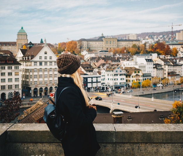 Jeune belle jolie fille touristique blonde en chapeau chaud et manteau avec sac à dos marchant à l'automne froid dans la ville d'Europe profitant de son voyage à Zurich Suisse