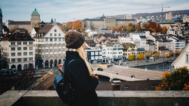 Jeune belle jolie fille touristique blonde en chapeau chaud et manteau avec sac à dos marchant à l'automne froid dans la ville d'Europe profitant de son voyage à Zurich Suisse