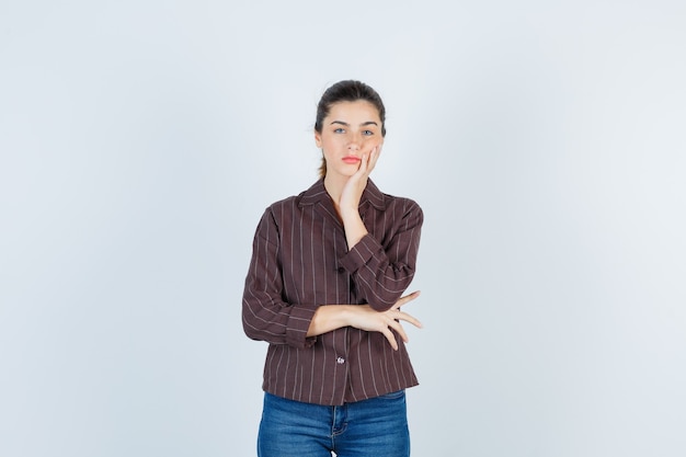 Jeune belle joue féminine appuyée sur la paume en veste et l'air pensif. vue de face.