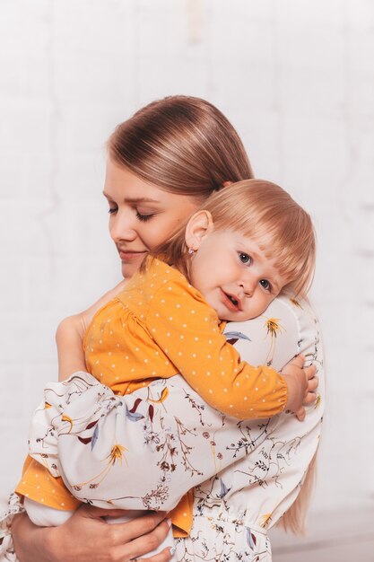 La jeune belle maman embrasse doucement sa petite fille. Verticale