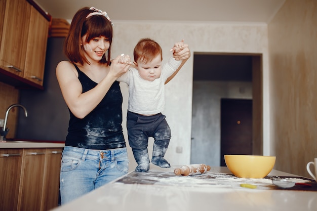 Une jeune et belle maman prépare la nourriture dans la cuisine, avec son petit fils