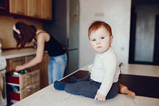 Une jeune et belle maman prépare de la nourriture à la maison dans la cuisine, avec son petit fils