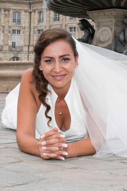 Photo jeune belle mariée avec coiffure et maquillage posant en robe blanche et voile