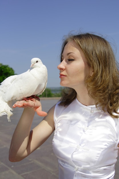 Jeune belle mariée tenant un pigeon blanc sur sa main