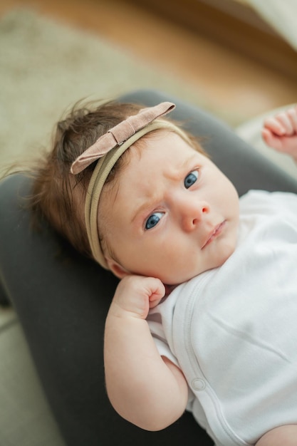 Jeune belle mère aux cheveux noirs tient sa fille nouveau-née dans ses bras dans une maison confortable Portrait de famille Maternité Jeune femme embrasse son bébé de 2 mois