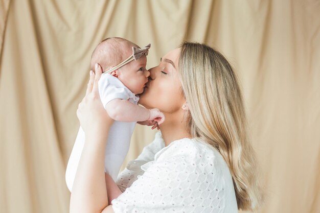 Jeune belle mère aux yeux bleus tient sa petite fille nouveau-née dans ses bras