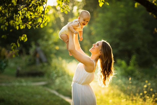 Jeune belle mère joue avec son enfant en plein air.