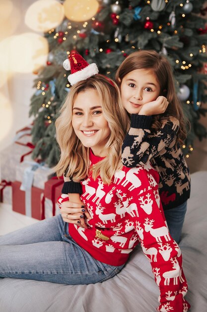 Jeune belle mère avec sa fille près de l'arbre de Noël