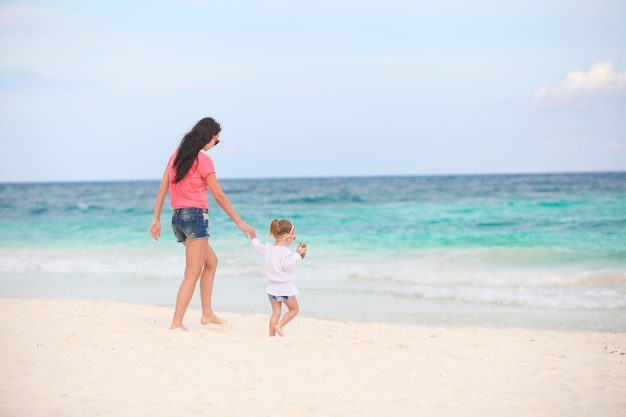 Jeune belle mère et son adorable petite fille qui longe la mer