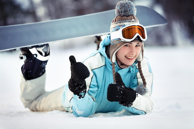 Jeune belle snowboardeuse se reposant sur une piste de ski