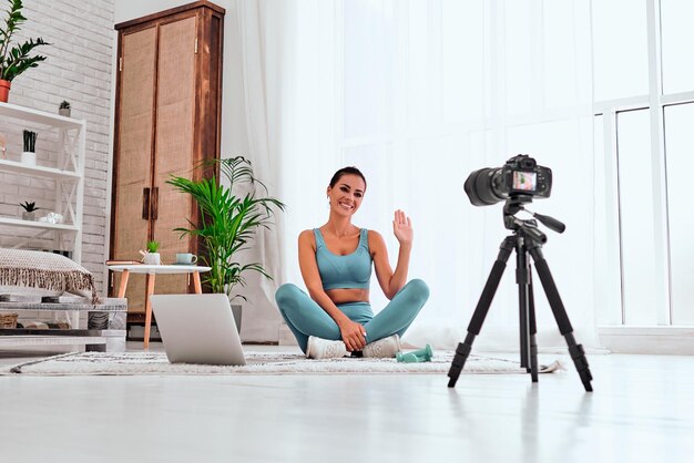 Jeune blogueur avec caméra sur trépied enregistrant un cours de fitness en ligne à la maison Espace de copie Prise de vue en contre-plongée