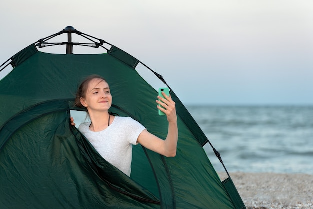 Jeune blogueur en tente sur la plage de sable