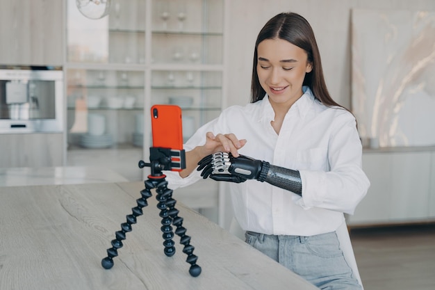 Jeune blogueuse handicapée montrant son bras robotique artificiel à ses abonnés à l'aide d'un smartphone