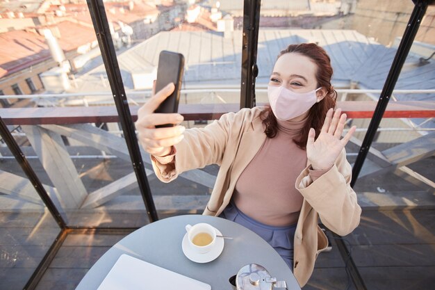 Jeune Blogueuse En Masque Menant La Diffusion En Direct Sur Son Téléphone Mobile En Se Tenant Debout Dans Un Restaurant élégant