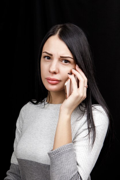 Jeune blogueuse de mode joyeuse et prospère parlant au téléphone, appréciant la conversation. Petite amie détendue insouciante dans un smartphone décontracté plus doux.