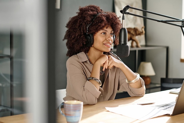 Photo jeune blogueuse souriante ou animatrice s'exprimant au micro au bureau