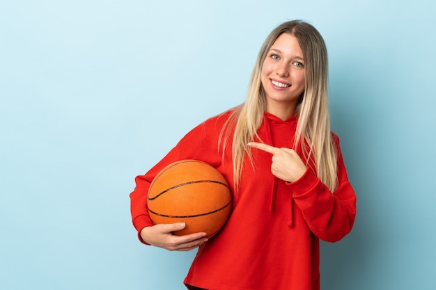 Jeune, blond, femme, isolé, bleu, mur, jouer, basket-ball, pointage, latéral