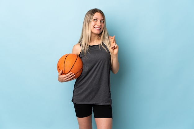 Jeune, blond, femme, jouer, basket-ball, isolé, bleu, mur, doigts, croisement