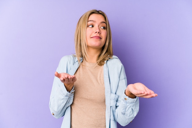 Jeune blonde caucasienne femme isolée doutant et haussant les épaules en remettant en question le geste.