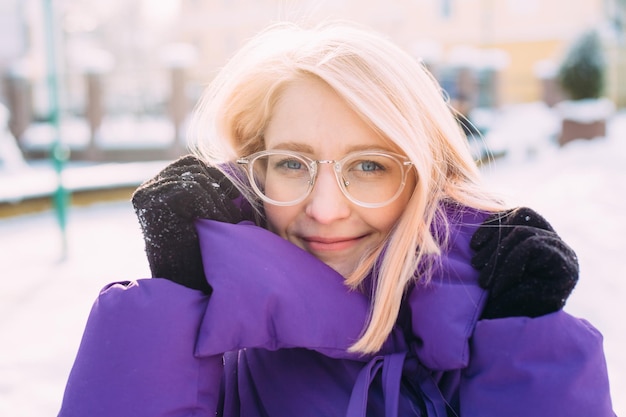 Jeune blonde élégante avec des lunettes dans la rue dans la neige