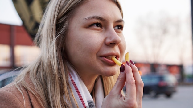Jeune blonde mangeant des frites au concept de restauration de rue de l'aire de restauration
