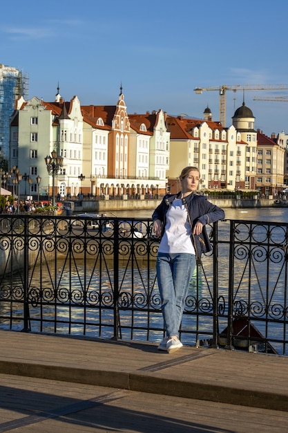 Une jeune blonde se dresse sur un pont sur fond de talus d'une belle ville