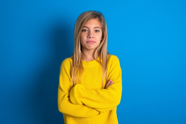 jeune blonde teen girl se tient les bras croisés montre une ambiance professionnelle se tient dans une pose affirmée