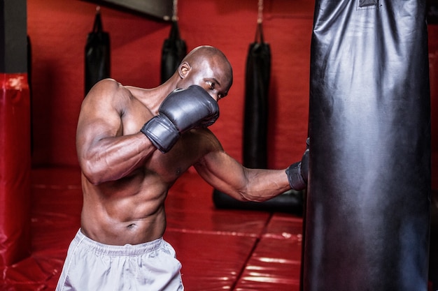 Jeune bodybuilder boxe un sac