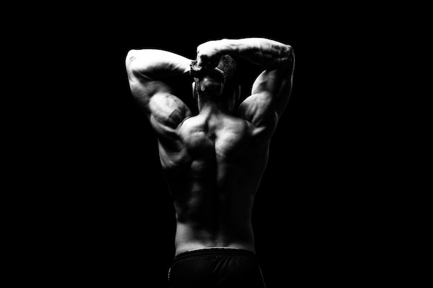 Jeune Bodybuilder Flexing Muscles Isoler sur l'espace de copie Black Blackground