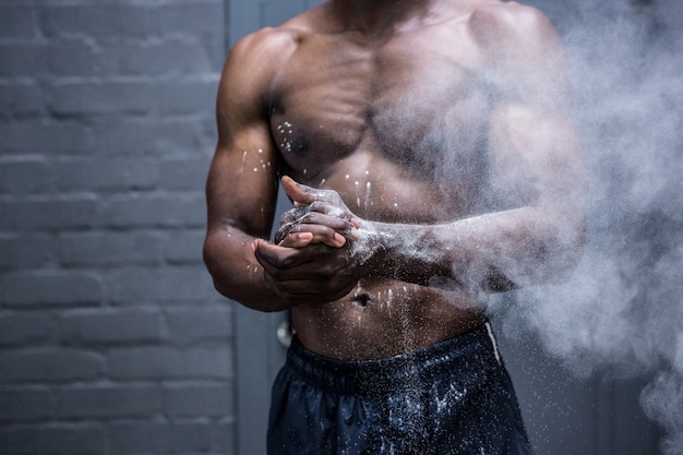 Jeune bodybuilder secouant la craie de ses mains