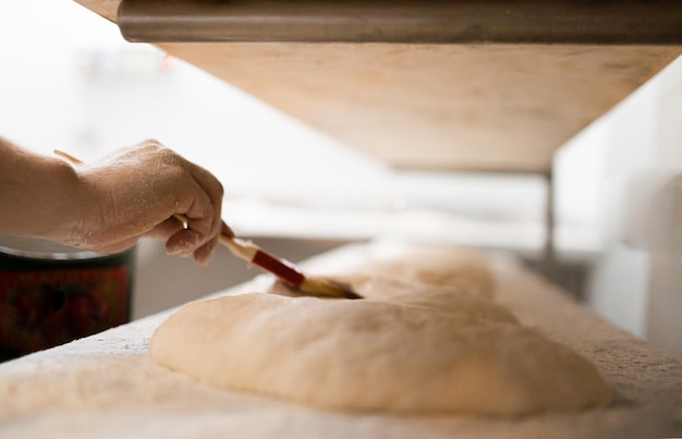 Le jeune boulanger place la pizza sur des planches de bois pour la faire monter et après la cuire boulangerie de pâte traditionnelle