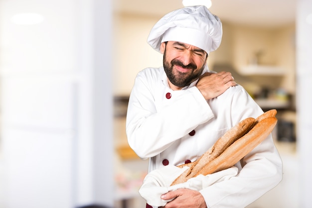 Le jeune boulanger prend du pain avec une douleur à l&#39;épaule dans la cuisine