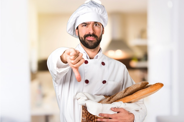 Le jeune boulanger prend du pain et fait du mauvais signal dans la cuisine