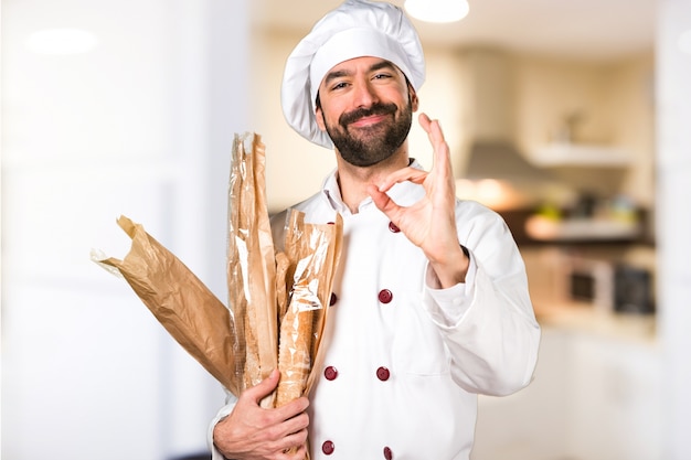 Le jeune boulanger prend du pain et signe OK dans la cuisine