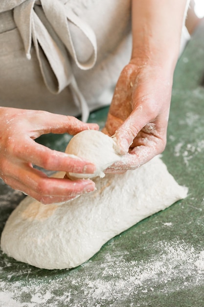 Jeune boulanger préparant des petits pains au levain artisanal.