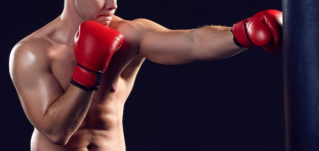 Jeune boxeur en gants rouges boxe sur fond noir