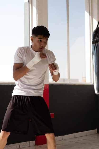 Jeune boxeur latino s'entraînant avec discipline et détermination sur son visage, vous pouvez voir sa concentration et qu'il a des objectifs clairs