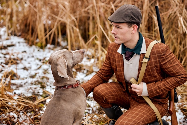 Jeune braconnier ou chasseur caucasien américain au chapeau avec un ami de race de chien pistolet et braque de Weimar dans le pays...