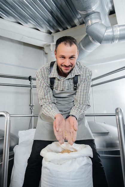 Un jeune brasseur détient un malt pour la bière. Brasserie.