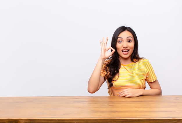 jeune brune à un bureau faisant signe correct avec la main