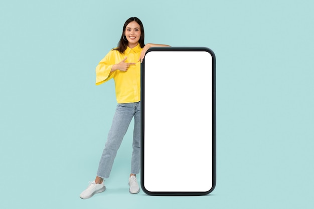 Une jeune brune élégante pointant du doigt un énorme téléphone