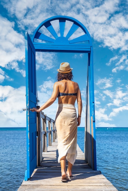 Une jeune brune passant une porte bleue dans la mer des Caraïbes sur l'île de Roatan. Honduras