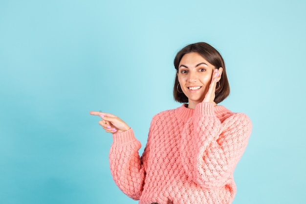 Jeune brune en pull rose isolé sur mur bleu