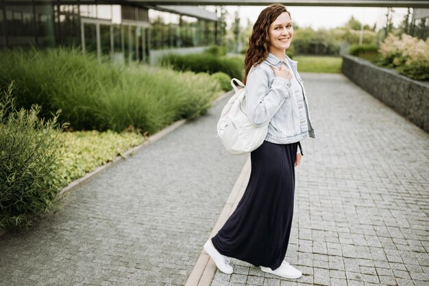 Une jeune brunette heureuse avec un sac à dos.