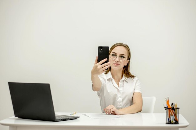 Jeune cadre supérieur au bureau sur son lieu de travail tenant un téléphone à la main et parlant par vidéo Le cadre supérieur parlant par téléphone décide des questions