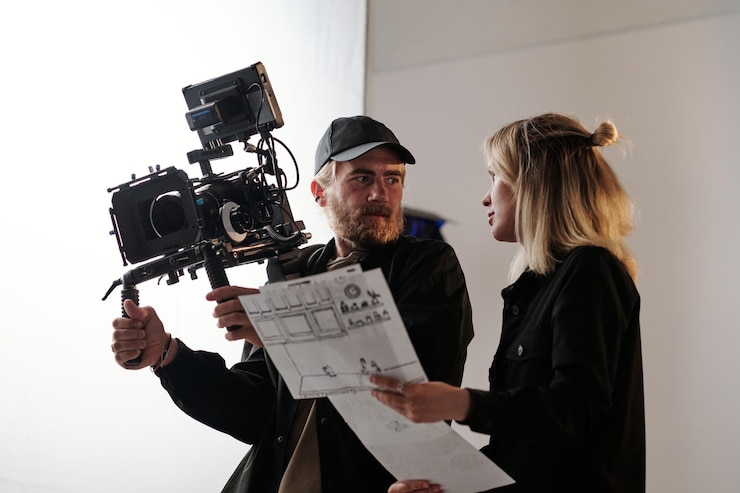 Photo jeune caméraman barbu et son assistant consultant sur le tournage