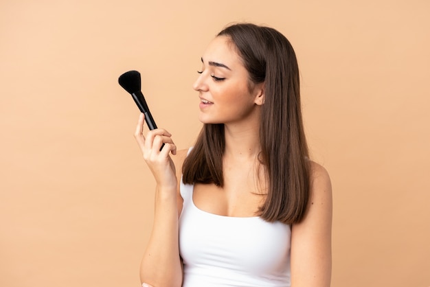 Jeune, caucasien, femme, isolé, beige, mur, tenue, maquillage, brosse