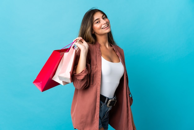 Jeune, caucasien, femme, isolé, sur, bleu, tenue, sacs provisions, et, sourire